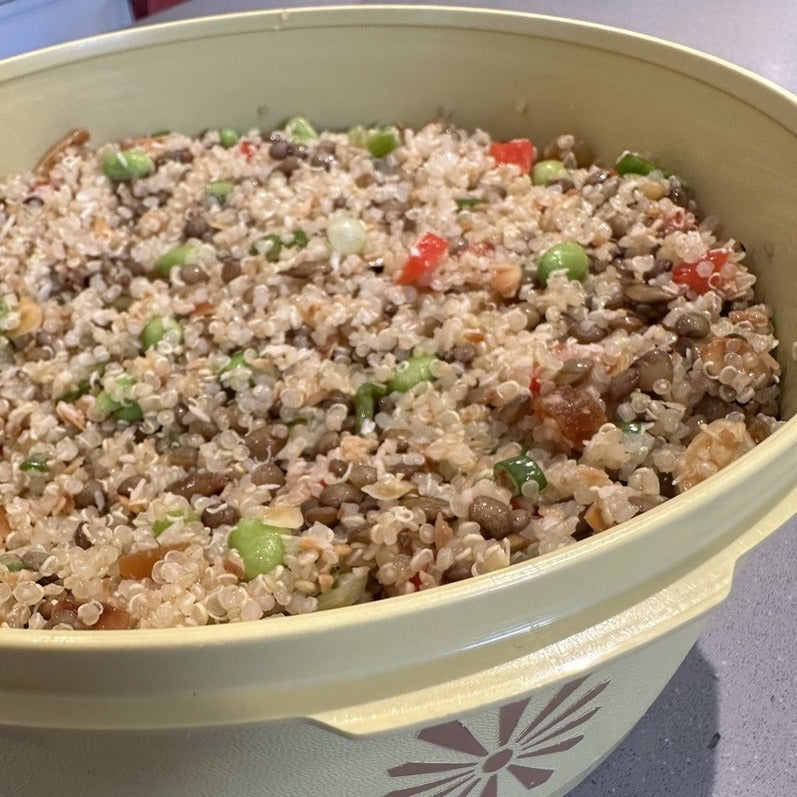 Quinoa, lentils, red pepper, edamame all mixed together in a vintage tupperware bowl. 
