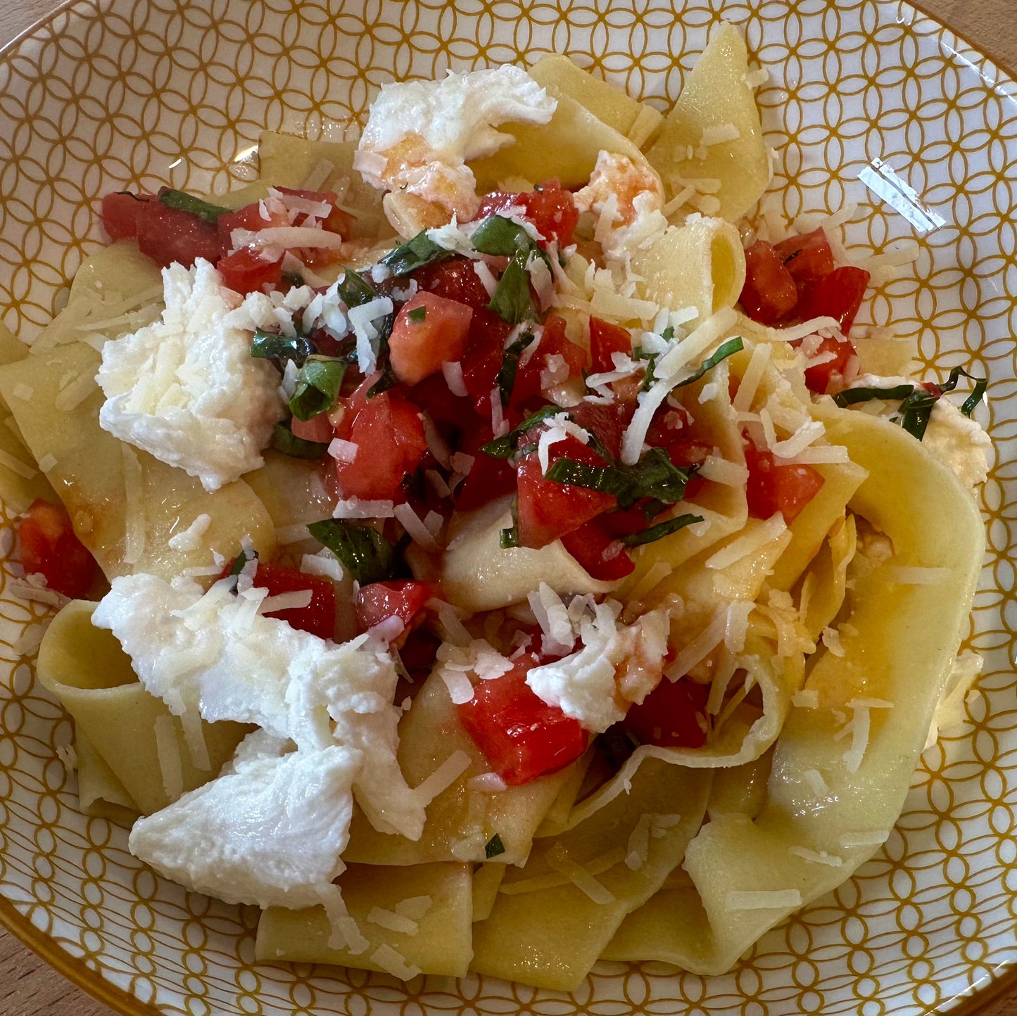 a yellow plate with fresh pasta, mozzarella and diced tomato sauce